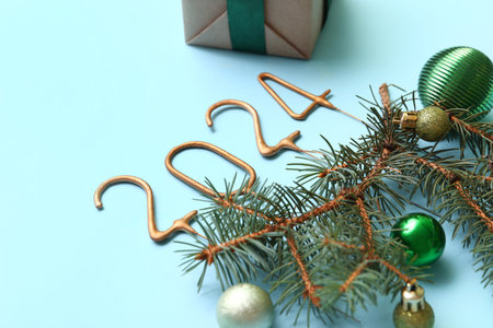 Figure 2024 made of sparklers with Christmas balls, fir branches and gift box on blue backgroundの写真素材