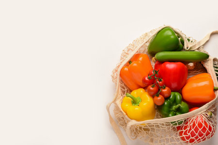 Mesh bag with different fresh vegetables on white backgroundの写真素材