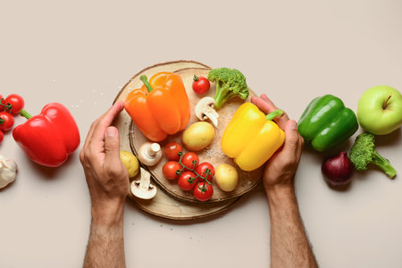 Man with different fresh vegetables on beige backgroundの写真素材