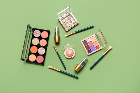 Beautiful palettes of eyeshadows and different decorative cosmetics on green backgroundの写真素材