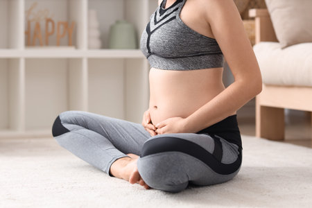 Sporty young pregnant woman sitting at home