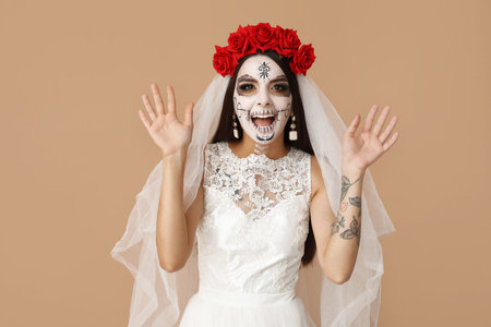 Beautiful young woman dressed as dead bride for Halloween party on beige background