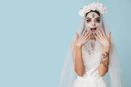 Beautiful shocked young woman dressed as dead bride for Halloween party on blue backgroundの写真素材