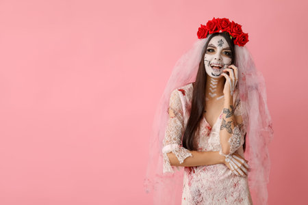 Beautiful young woman dressed as dead bride for Halloween party on pink background