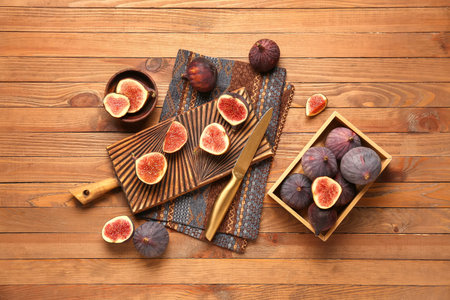 Board and box with fresh ripe figs on wooden background