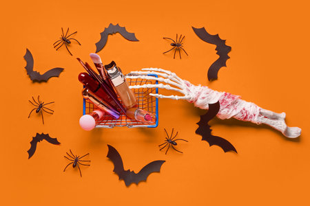 Composition with shopping basket full of cosmetics and Halloween decorations on color backgroundの写真素材