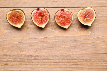 Halves of fresh ripe figs on wooden background