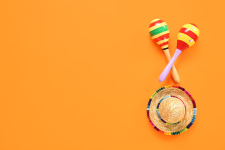 Mexican maracas with sombrero hat for Independence Day on orange background