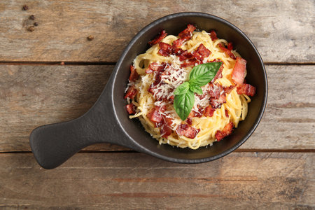 Frying pan with tasty pasta carbonara on wooden backgroundの写真素材