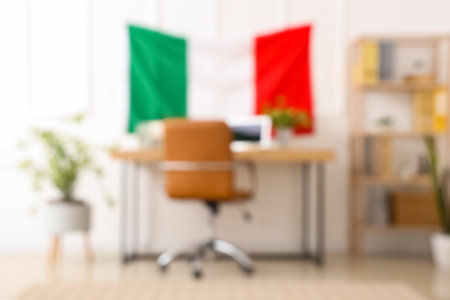 Modern workplace with laptop, stationery and hanging Italian flag in office, blurred viewの写真素材