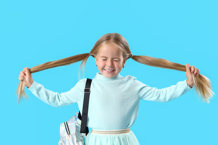 Cute little girl with backpack on blue backgroundの写真素材