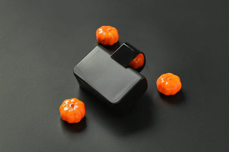 Bottle of elegant perfume with pumpkins for Halloween celebration on black background