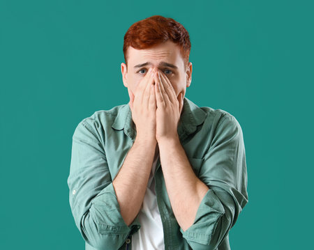 Fearful young man on green backgroundの写真素材