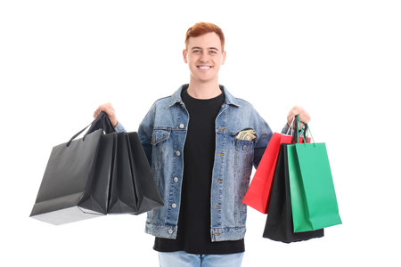 Happy young redhead man with shopping bags isolated on white background. Black Friday saleの写真素材