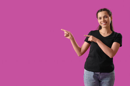 Beautiful young woman pointing at something on purple background. Black Friday saleの写真素材