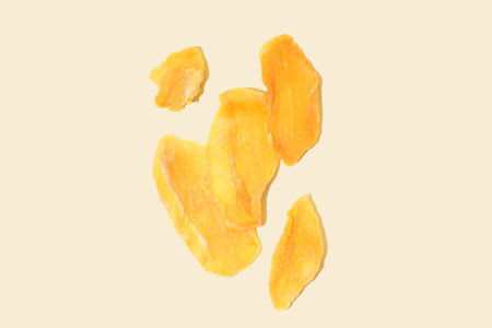 Slices of dried mango on yellow backgroundの写真素材