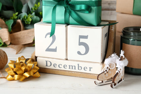 Decorations, gift boxes, candle and calendar with date of Christmas on wooden background