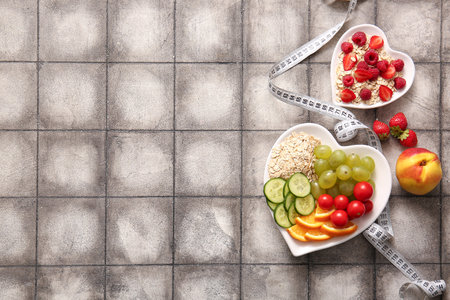 Plates with fresh healthy products and measuring tape on gray tile background. Diet conceptの写真素材