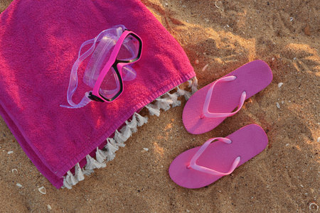 Stylish pink female flip flops, towel and snorkeling mask on sandの写真素材