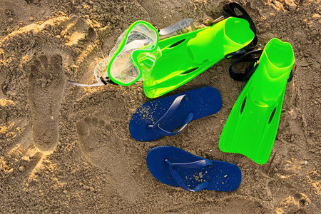 Stylish female flip flops, flippers and snorkeling mask on sandの写真素材