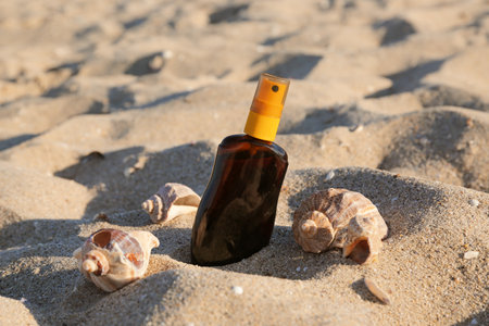 Bottle of sunscreen cream with seashells on sand at beachの写真素材