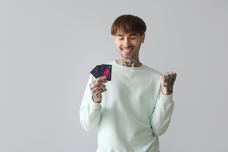 Happy young man with credit cards on light backgroundの写真素材