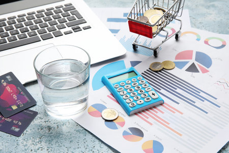 Glass of water, credit cards, calculator and charts on blue grunge table. House rent conceptの写真素材