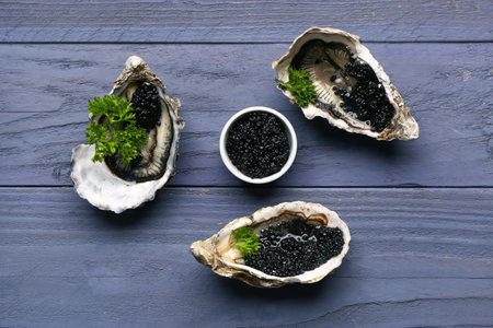 Tasty oysters with black caviar on blue wooden backgroundの写真素材