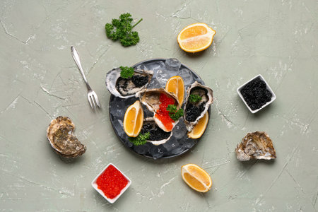 Plate of tasty oysters with lemon, black and red caviar on gray backgroundの写真素材