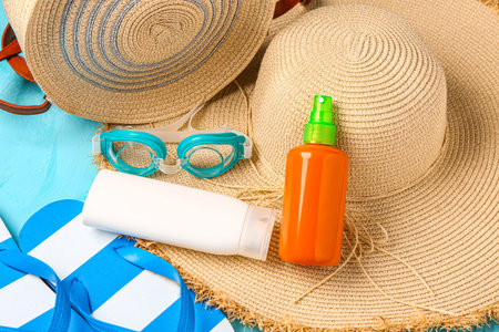 Bottle of sunscreen cream with beach accessories on grunge blue background