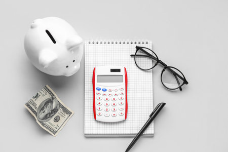 Calculator, notebook and piggy bank on gray backgroundの写真素材