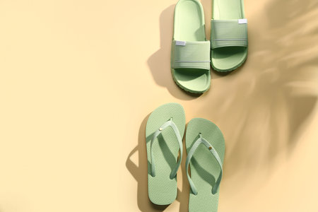 Female stylish flip flops on pale yellow backgroundの写真素材