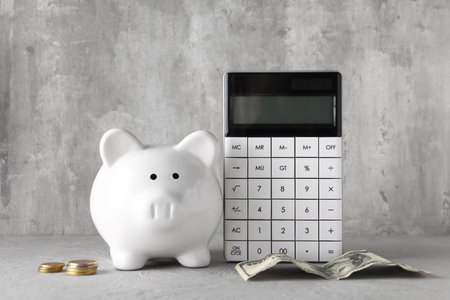 Calculator, piggy bank and money on gray grunge backgroundの写真素材