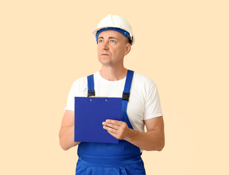 Mature worker with clipboard on beige background. Labor Day celebrationの写真素材