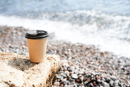 Takeaway cup of hot coffee on the beachの写真素材