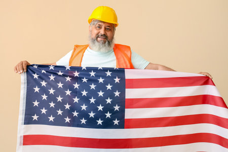 Portrait of senior man in hardhat with USA flag on beige background. Labor Day celebrationの写真素材