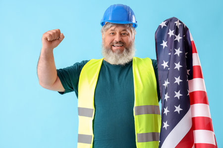Portrait of happy senior man in hardhat with USA flag on blue background. labor day celebrationの写真素材