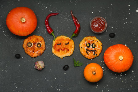 Composition with different tasty Halloween mini pizzas, pumpkins and sauce on dark backgroundの写真素材