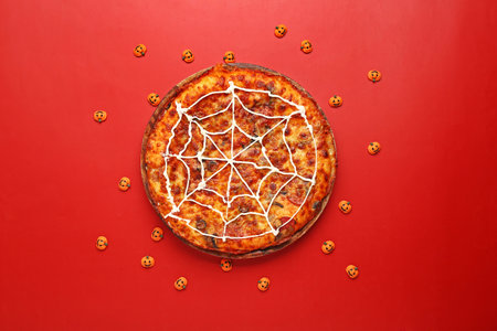 Wooden board with tasty pizza and pumpkins for Halloween party on red backgroundの写真素材