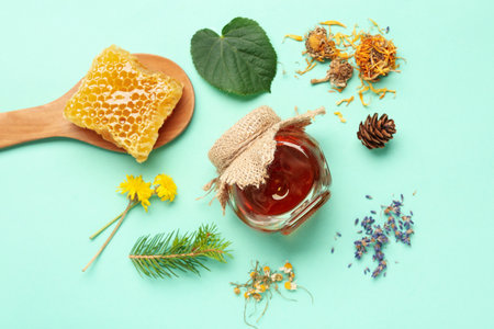 Jar with tasty honey, honeycomb and dried flowers on turquoise backgroundの写真素材