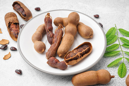 Plate of tasty tamarinds, seeds and leaf on white backgroundの写真素材