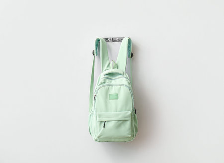 Stylish school backpack hanging on light wall