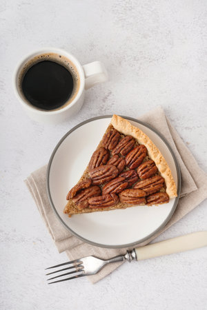 Plate with tasty pecan pie and cup of coffee on light backgroundの写真素材