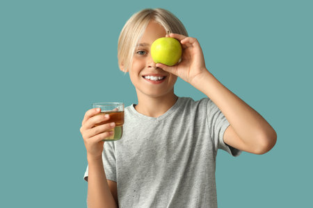 Little boy with glass of juice and apple on blue backgroundの写真素材