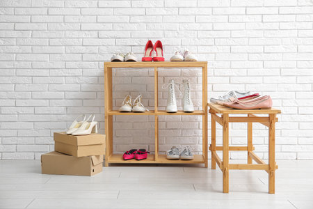 Wooden shelving units with stylish female shoes near light brick wall in storeの写真素材