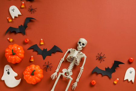 Composition with tasty candy corns, cookies, skeleton and Halloween decor on brown background