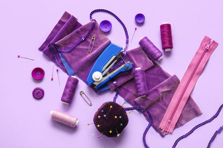 Manual sewing machine with various supplies on lilac backgroundの写真素材