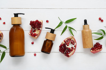 Composition with cosmetic products, pomegranate and plant leaves on light wooden backgroundの写真素材