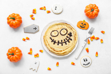Composition with funny Halloween pancakes, sweets and decorations on light backgroundの写真素材