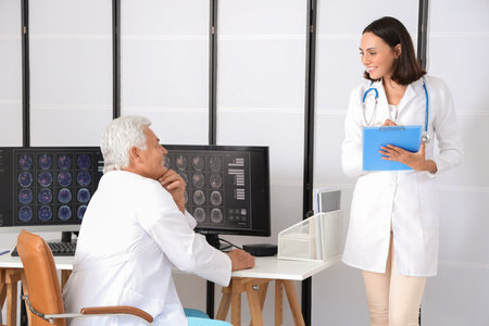 Doctors discussing x-ray image on computer in medical officeの写真素材